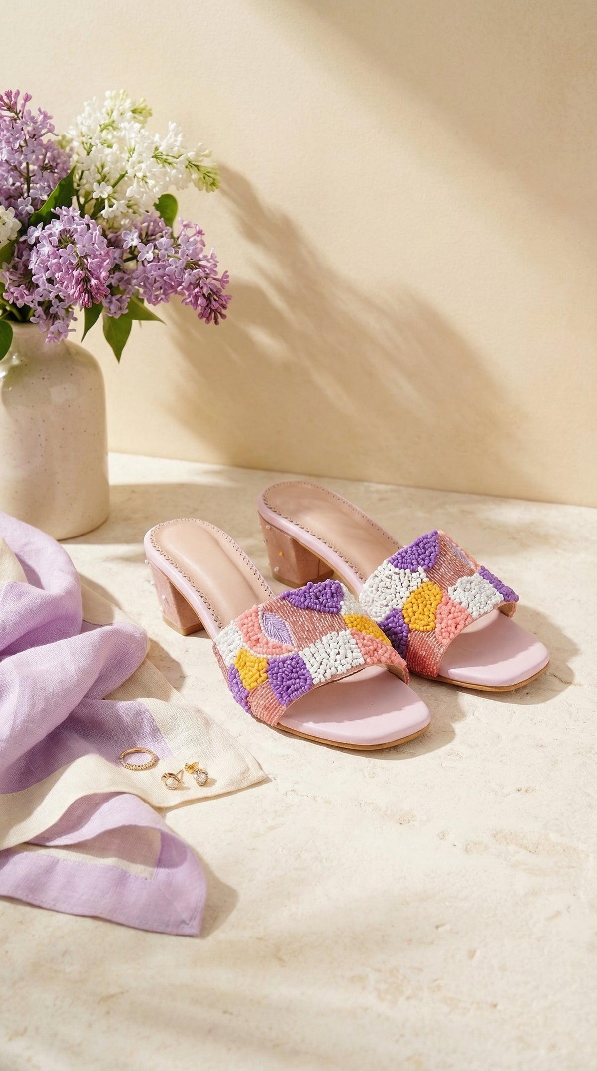 Phulkari 2.0 Blush Pink Pastel Checkerboard Punch Needle Heel Slide by Radiarte – Flat Lay with Lilac Flowers & Gold Rings