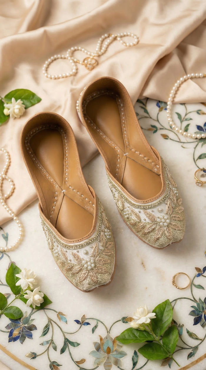 Tara ivory gold zardozi pearl jutti by Radiarte – top view flat lay on pietra dura marble with pearls and jasmine