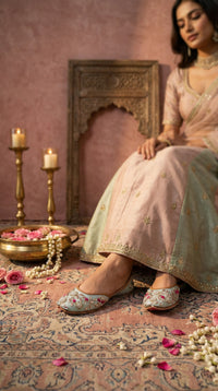 Samundar powder blue jutti worn with pink lehenga – model seated in bridal setting with roses Radiarte