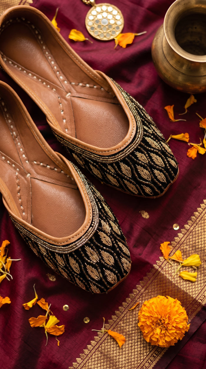 Shabnoor black velvet gold leaf embroidered jutti pair flat lay