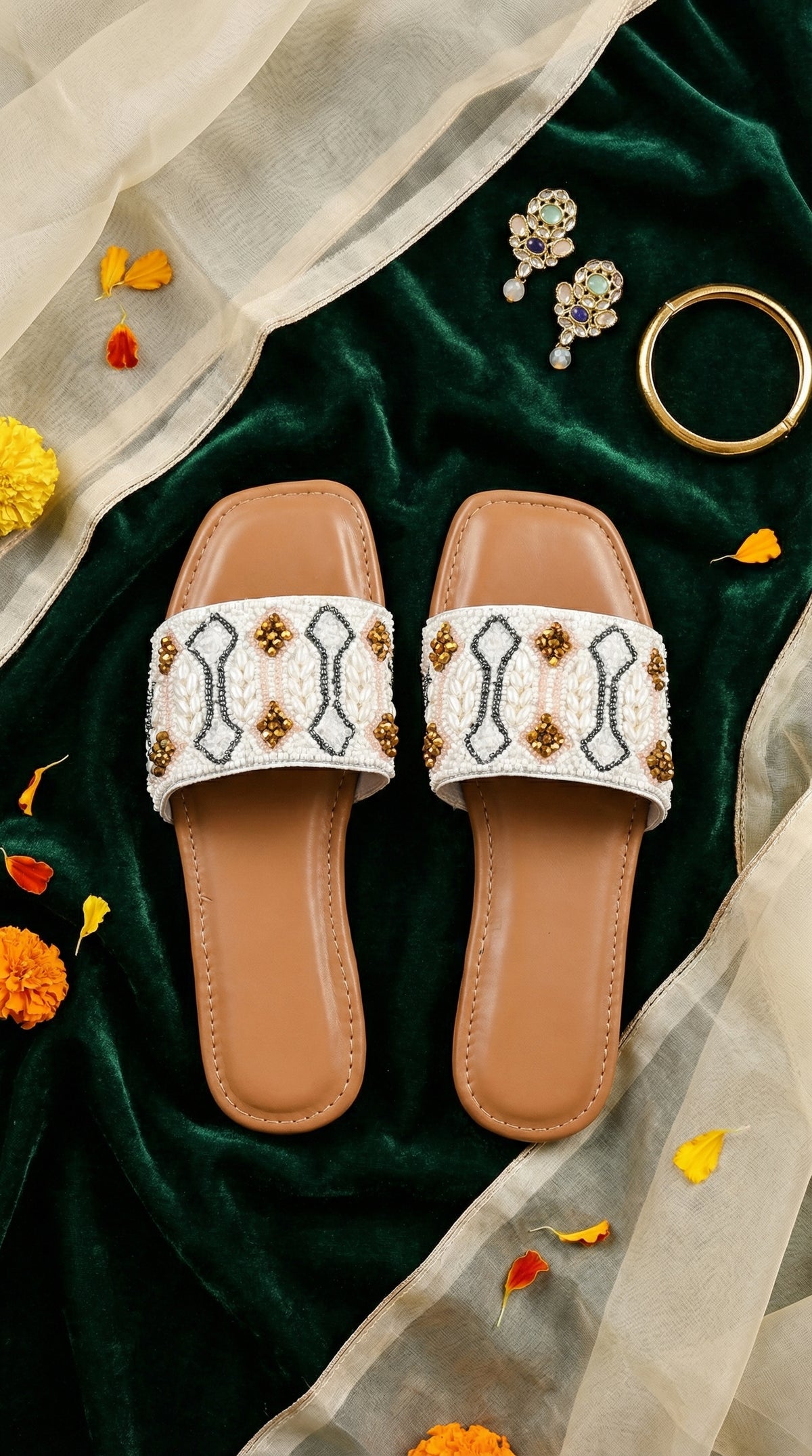 Taj white pearl beaded slide flat by Radiarte – top view flat lay on green velvet with gold jewellery and marigolds