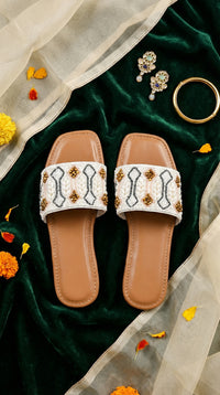 Taj white pearl beaded slide flat by Radiarte – top view flat lay on green velvet with gold jewellery and marigolds