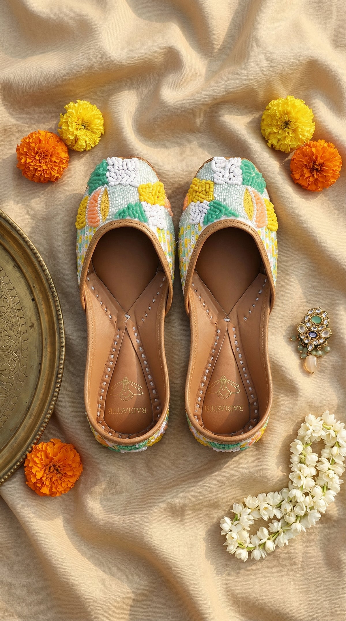 Zale pastel multicolour French knot sequin jutti by Radiarte – top view flat lay on champagne silk with marigolds and mogra