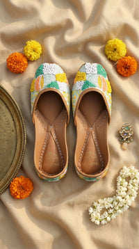 Zale pastel multicolour French knot sequin jutti by Radiarte – top view flat lay on champagne silk with marigolds and mogra