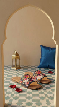 Rangrez floral thread work slide flat – arched doorway display with blue cushion and rose petals