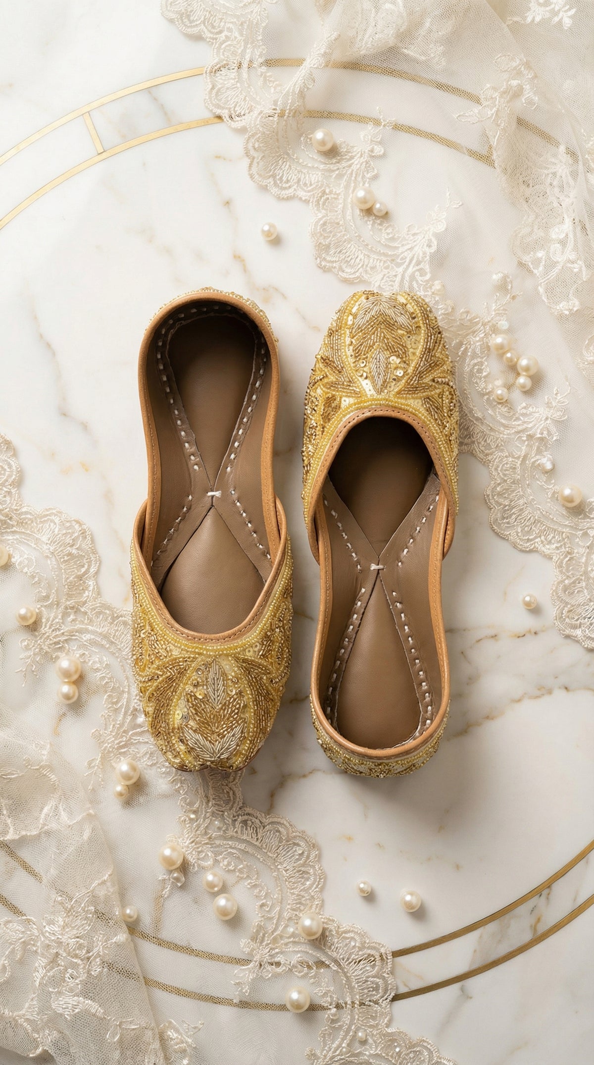 Shararat handcrafted gold bridal jutti – top view flat lay on marble with lace and pearls by Radiarte