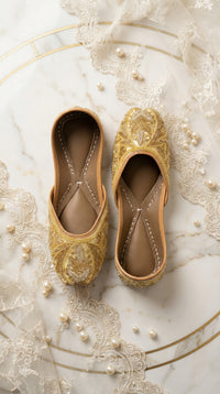 Shararat handcrafted gold bridal jutti – top view flat lay on marble with lace and pearls by Radiarte