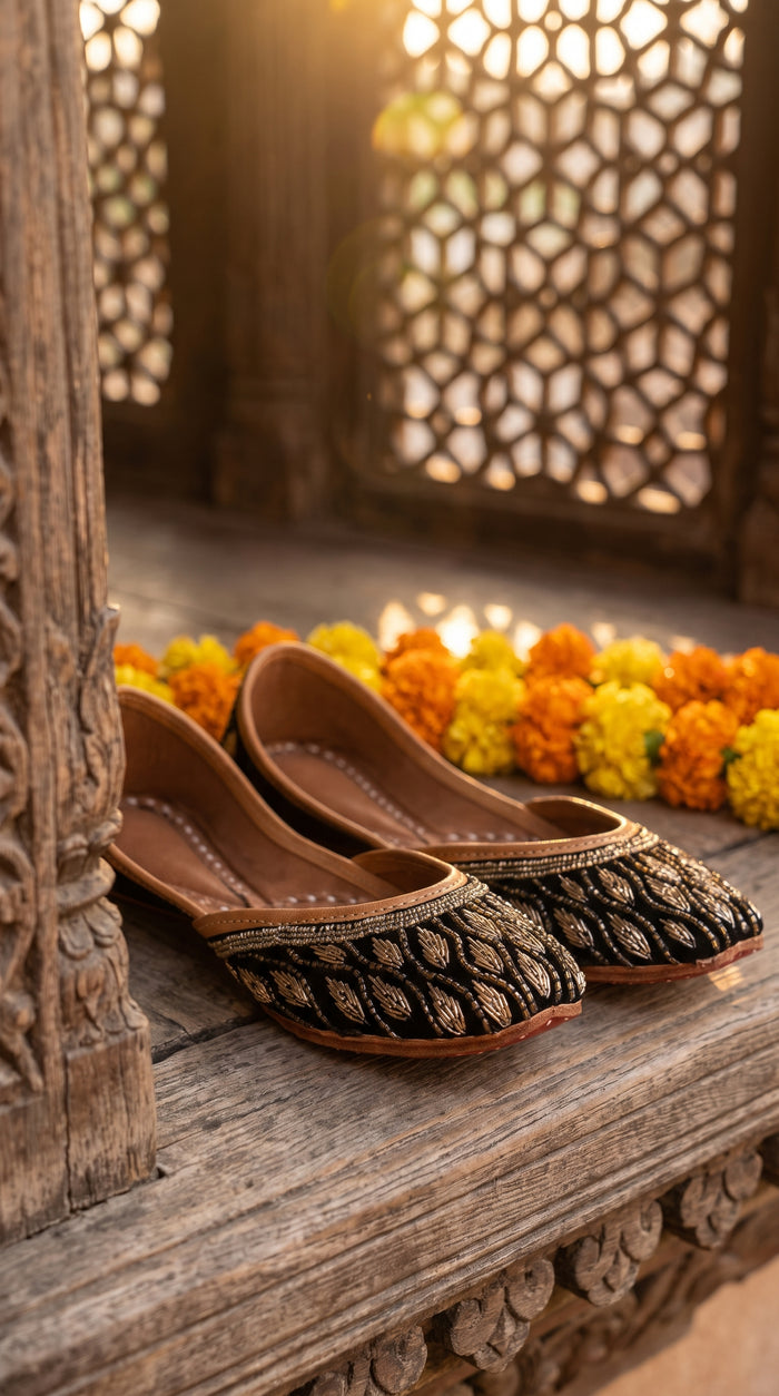 Shabnoor handcrafted juttis on wooden haveli ledge with marigolds