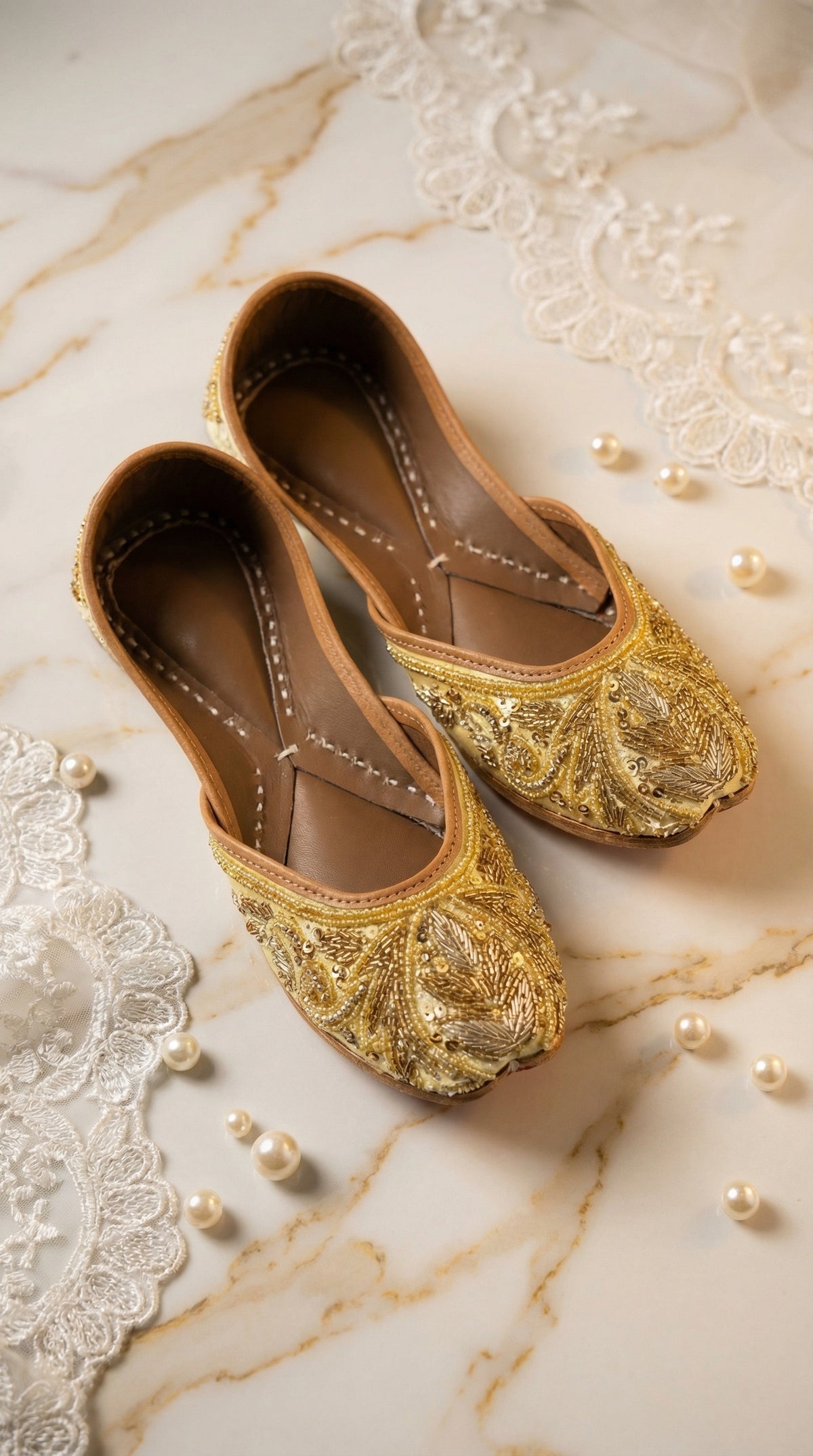 Shararat gold sequin zardozi jutti – top angle flat lay on marble with scattered pearls Radiarte