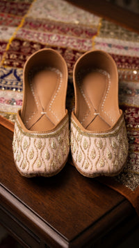 Pallavi blush pink gold beaded jutti pair on embroidered bridal fabric