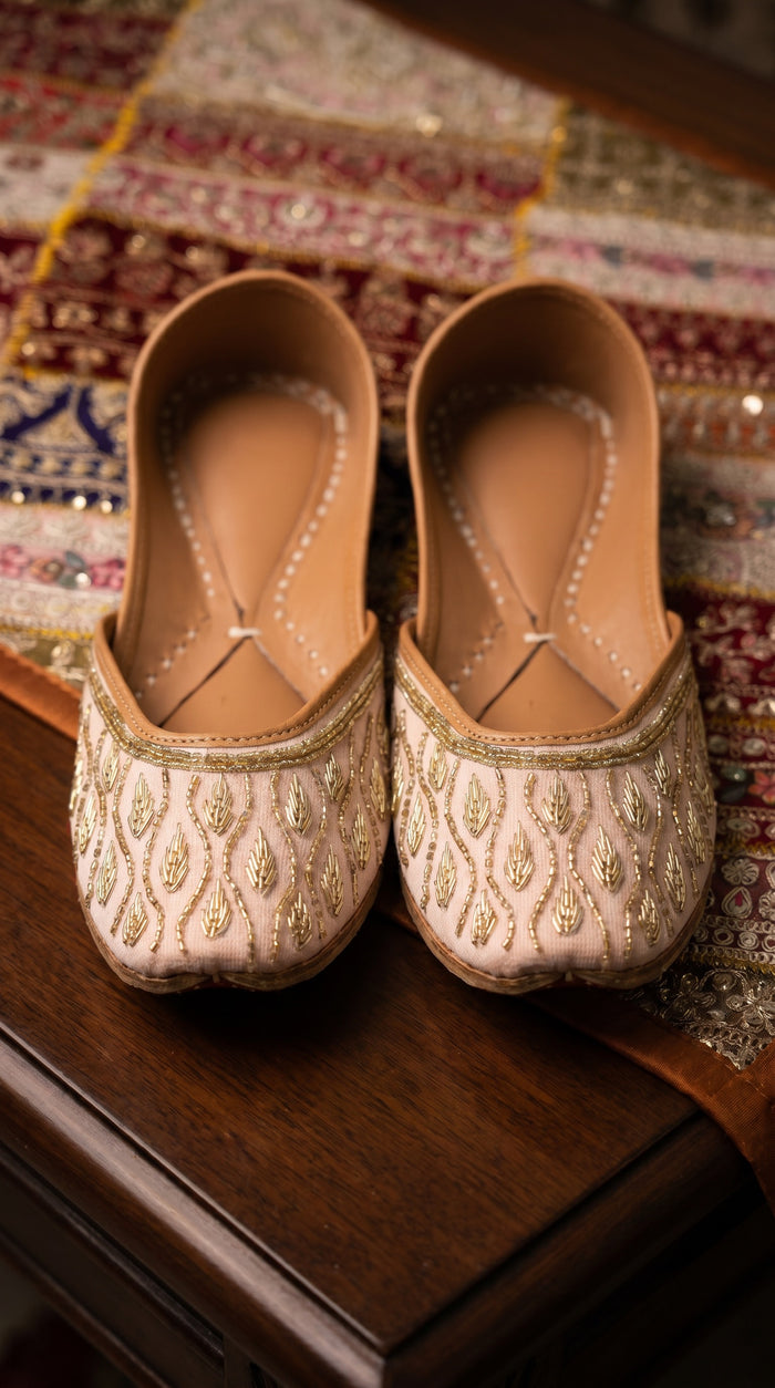 Pallavi blush pink gold beaded jutti pair on embroidered bridal fabric