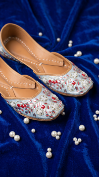 Samundar powder blue floral embroidered jutti by Radiarte – diagonal pair view on royal blue velvet with scattered pearls