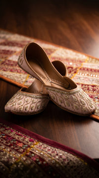 Pallavi blush pink jutti worn on feet with gold embroidered bridal lehenga