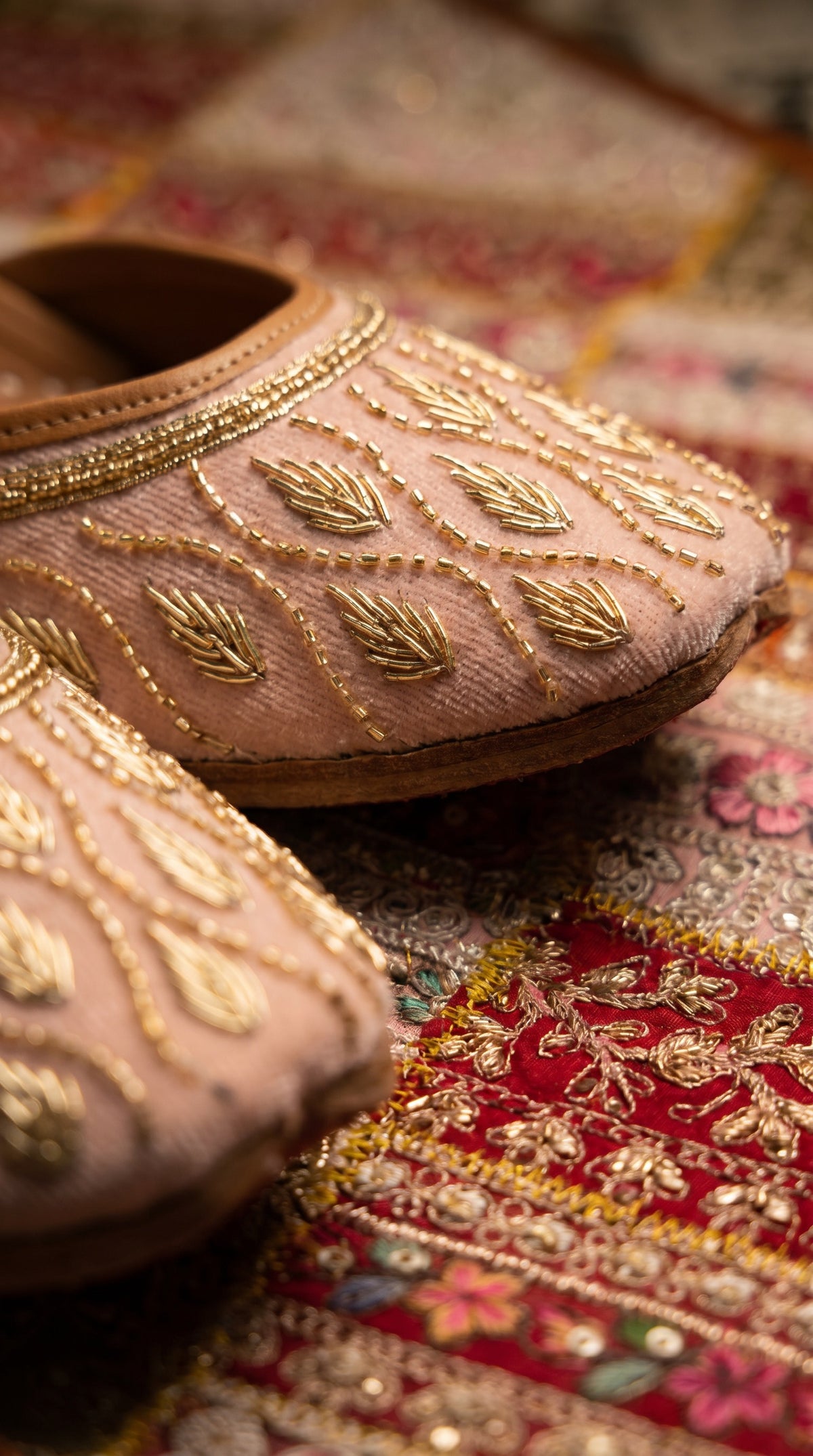 Pallavi gold beaded jutti pair styled on vintage table with bridal dupatta